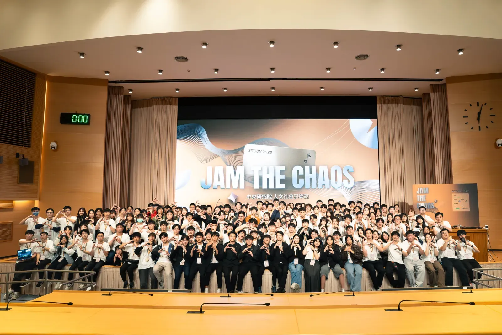 SITCON 年會參與者在「Jam the Chaos」主視覺前的舞台大合照